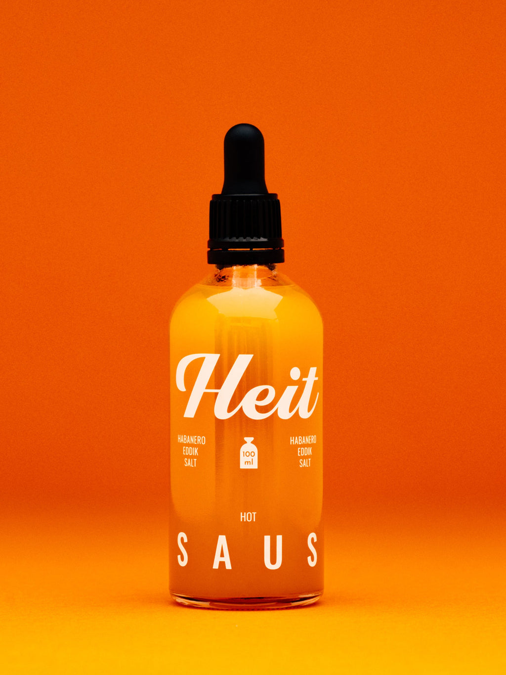 Flaske Heit Hot saus mot oransje bakgrunn